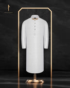 White coat on a mannequin with a gold stand against a dark background